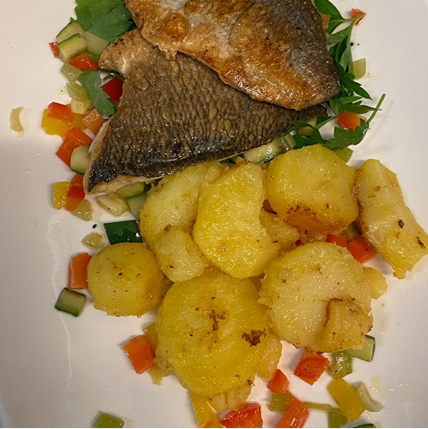 Fischgericht mit Beilage, mediterran angerichtet